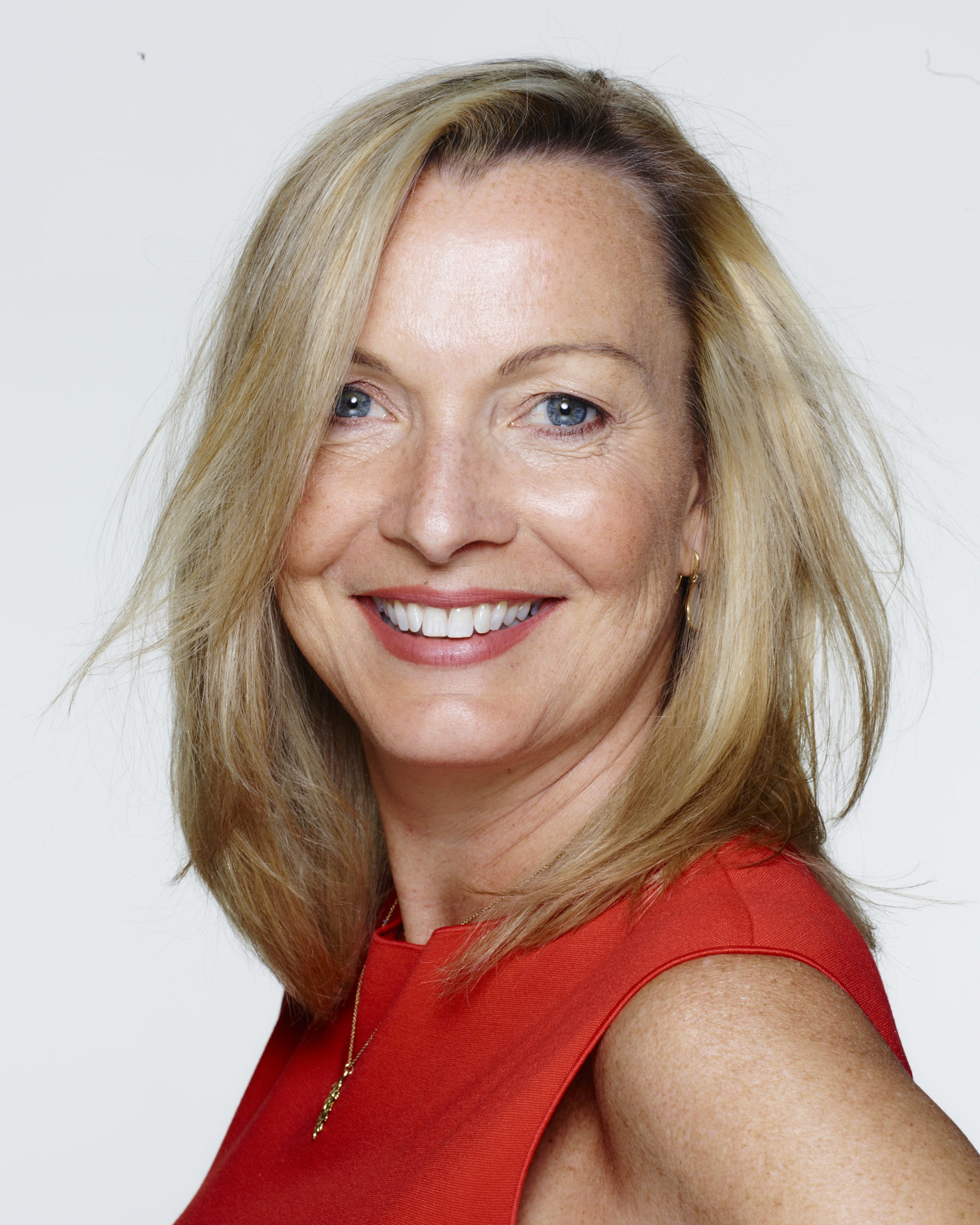 Suki looking at the camera, smiling, wearing a red dress.