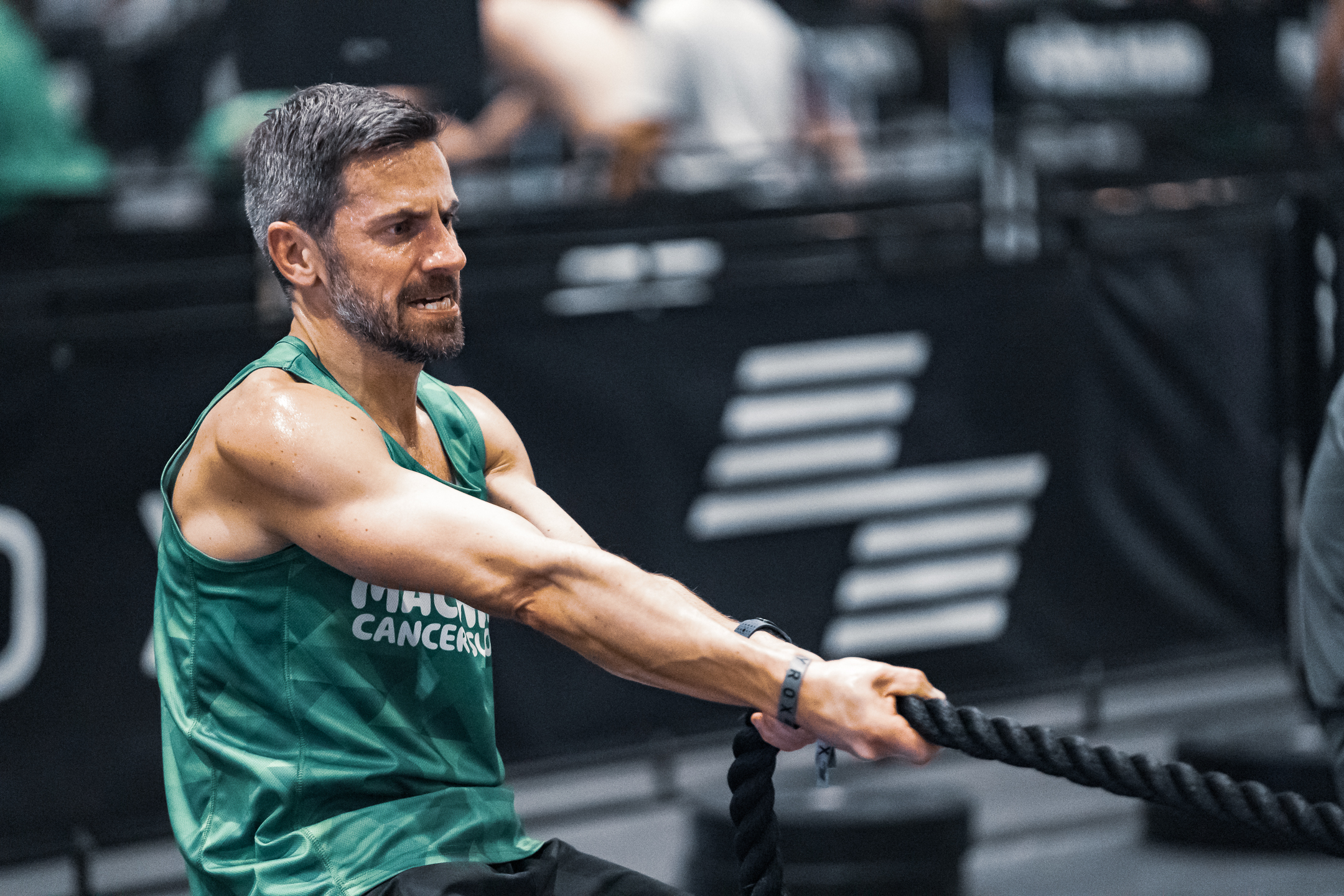A man wearing a Macmillan vest doing a rope pull at a HYROX event