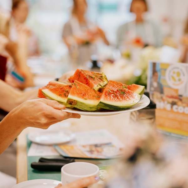 A person is holding up a plate of watermelon slices. Photography: Rebecca Maen