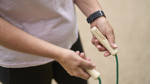 A close up photo of a person holding the ends of a skipping rope in their hands. One of the handles has Macmillan Cancer Support embossed on it.