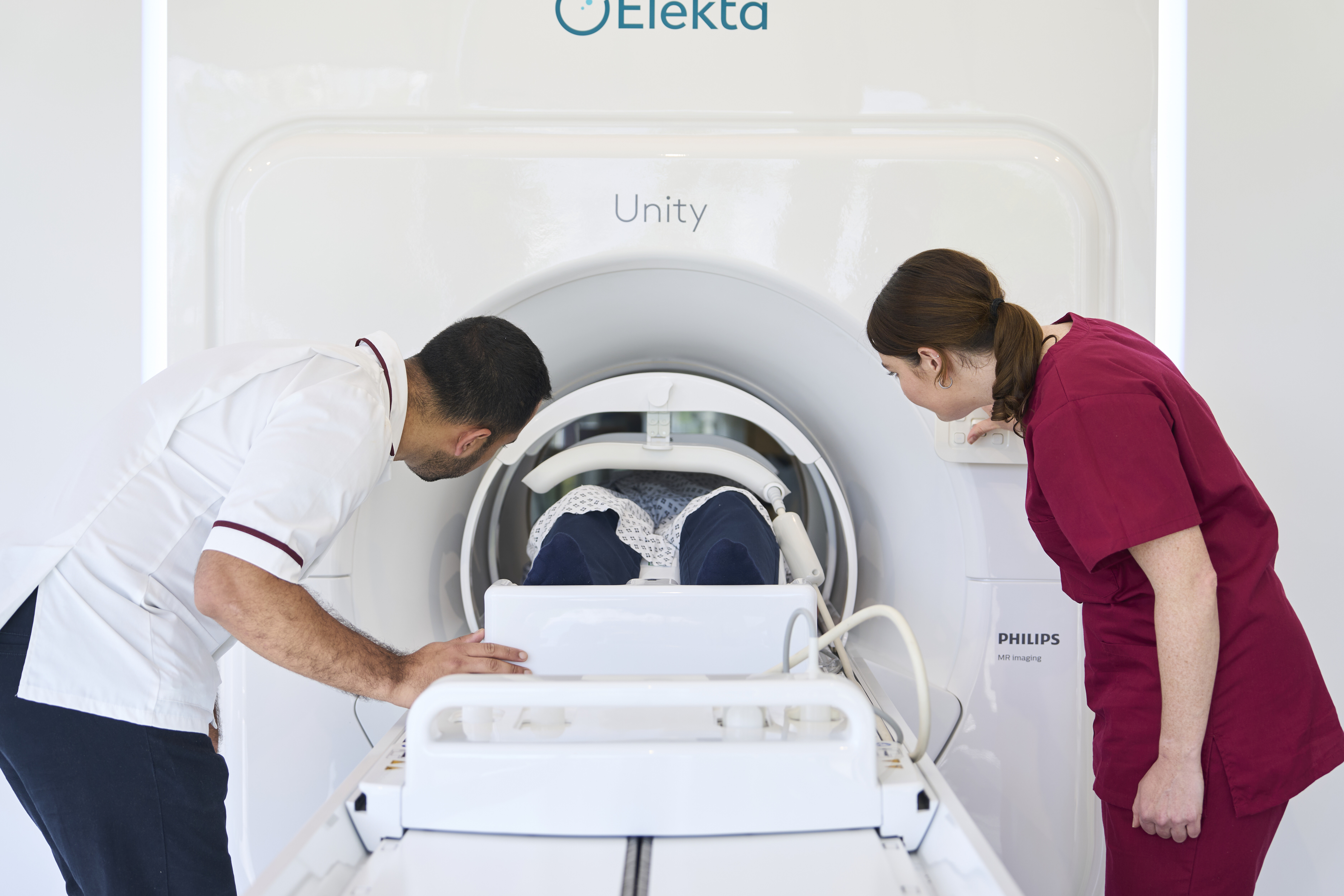 Two healthcare professionals assisting a patient undergoing an MRI scan 