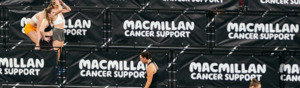A wide view of a HYROX event which shows dividers between fitness sections with the Macmillan logo on them.