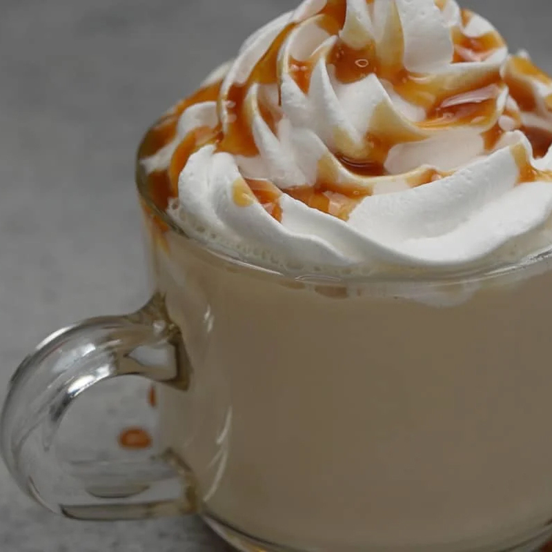 A freshly brewed cup of coffee topped with a thick dollop of whipped cream and moreish caramel drizzle. 