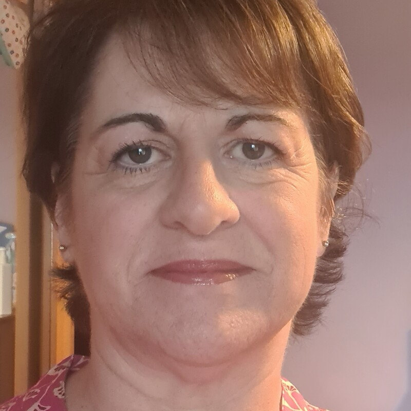 A selfie of Cathy. She has short brown hair and is wearing a pink top with a floral pattern on it.