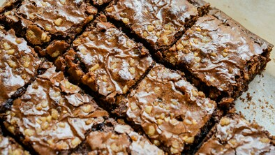 Rich and fudgy brownies are cut into square chunks and placed on white baking parchment. Photo by Michelle Tsang on Unsplash.       
