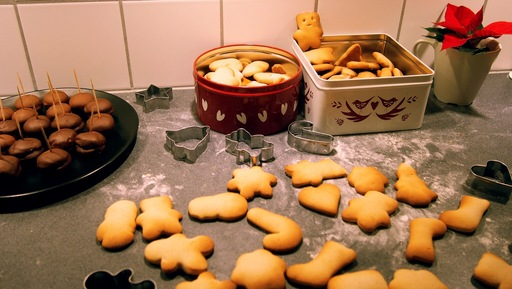 A countertop in a kitchen is covered in different baked goods after a baking session. There are tins filled with biscuits and a plan with a chocolate treat. 