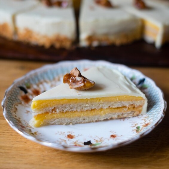 A slice of Swedish almond cake is placed on a delicate plate. It is covered in a light frosting and topped with a toasted almond. Photo by Patisserie Makes Perfect.