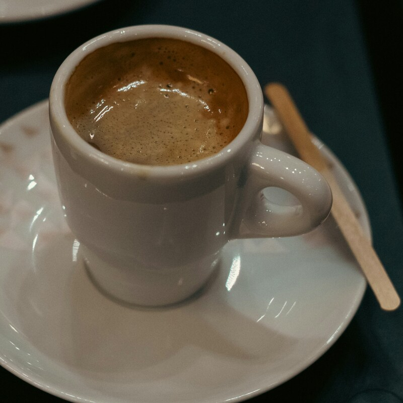 A small mug is full of freshly brewed coffee. Photo by Pedro Correia on Unsplash.