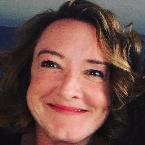 A lady with curly brown hair who is a Macmillan nurse on the helpline