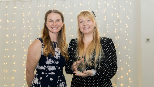 Lucy Best winner of the 2025 Macmillan Thanks to You Award - with Ambition, holding her award. Pictured with event host Erin Kennedy OBE on the left