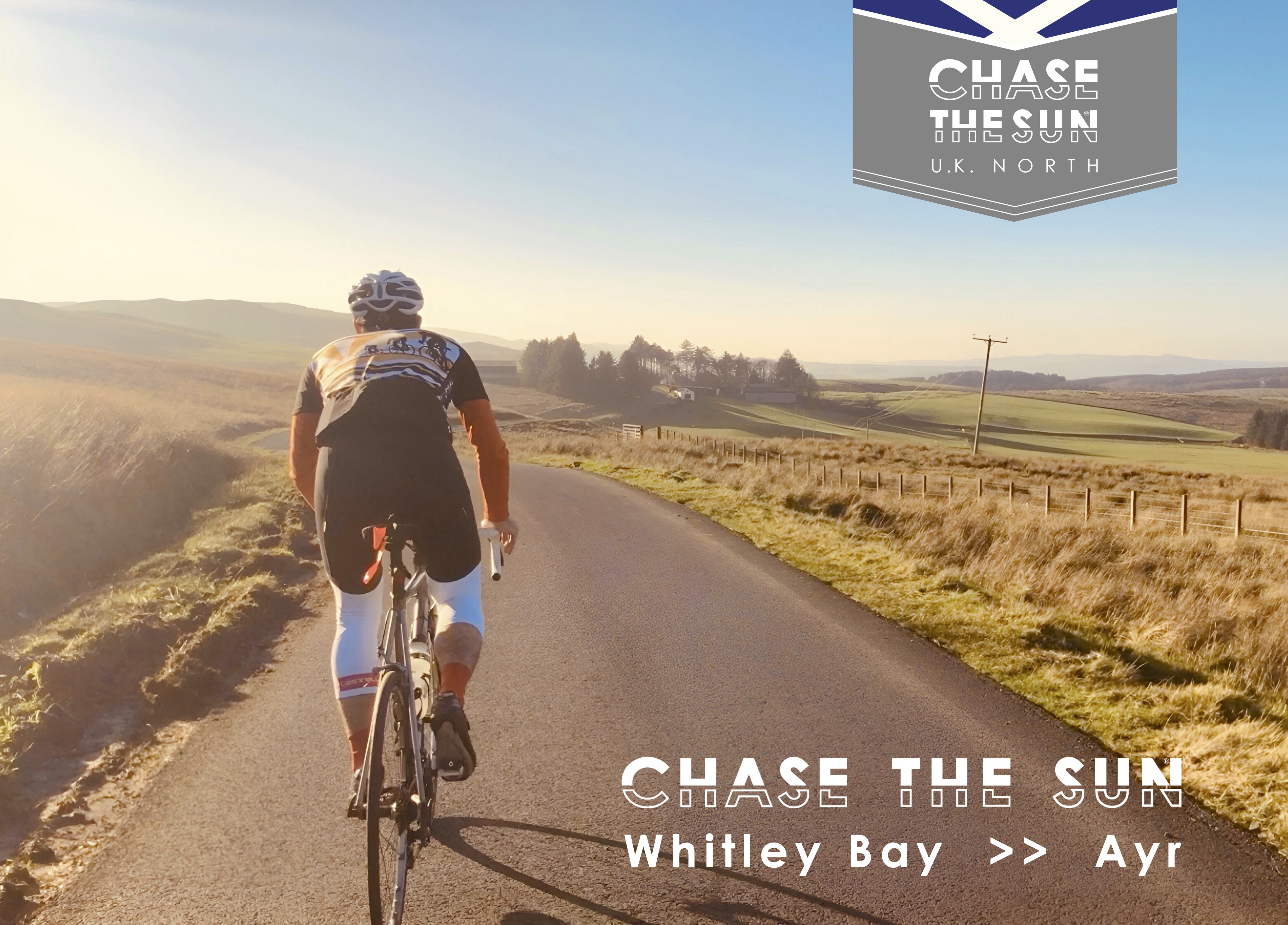 A person is seen cycling down a paved road in the countryside from behind. They are wearing cycling gear. The image also has text on it that includes the Chase the Sun UK North logo and Chase the Sun Whitley Bay to Ayr.