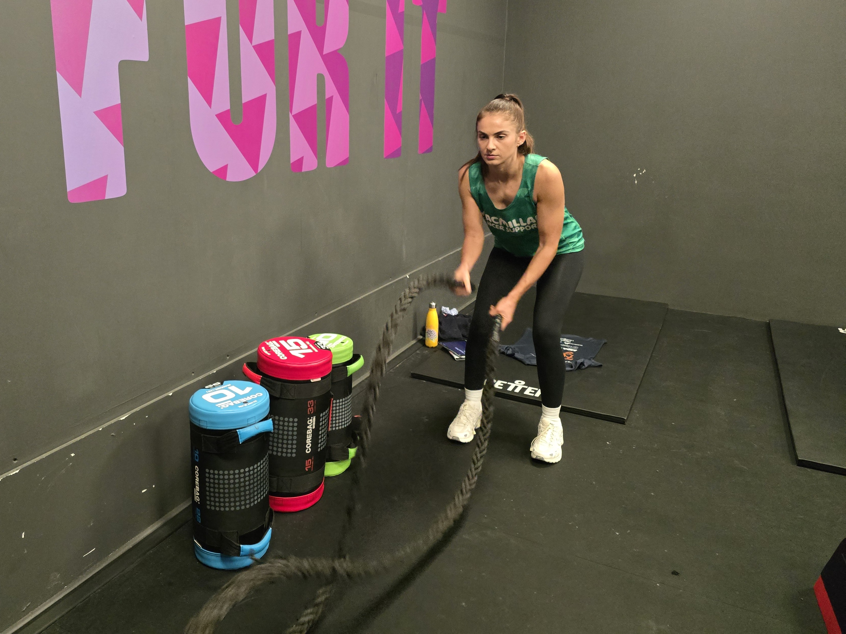 A woman in a gym setting using battle ropes
