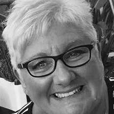 A black and white photo of Carol. She has short hair and is wearing black rimmed glasses.