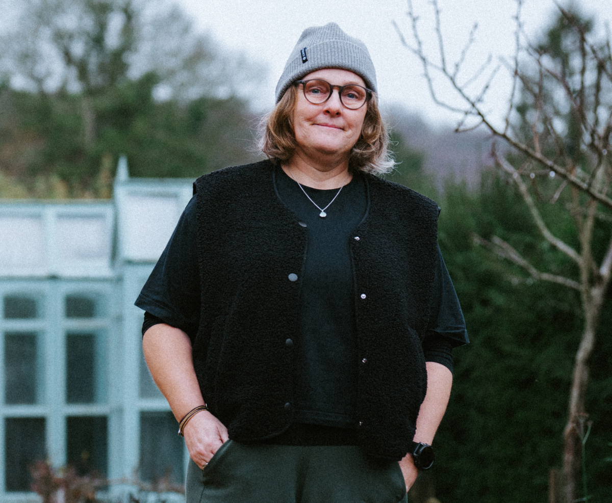 A woman in glasses and a beanie hat, smiling in an outdoor setting.