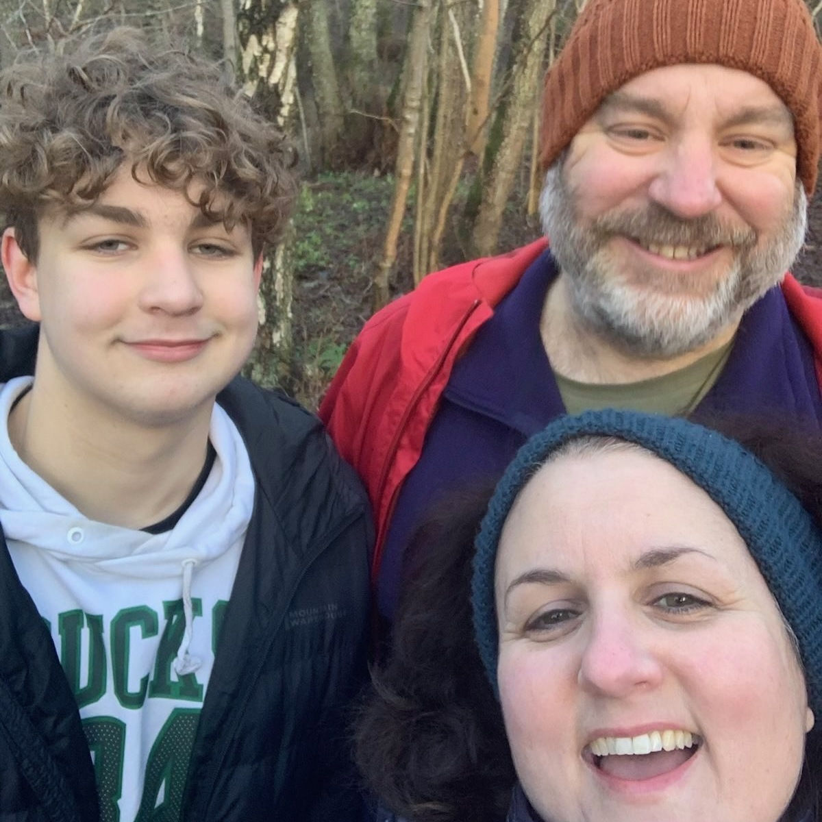 Jon is a white man with a beard wearing a woolly hat, with his wife and teenage son.