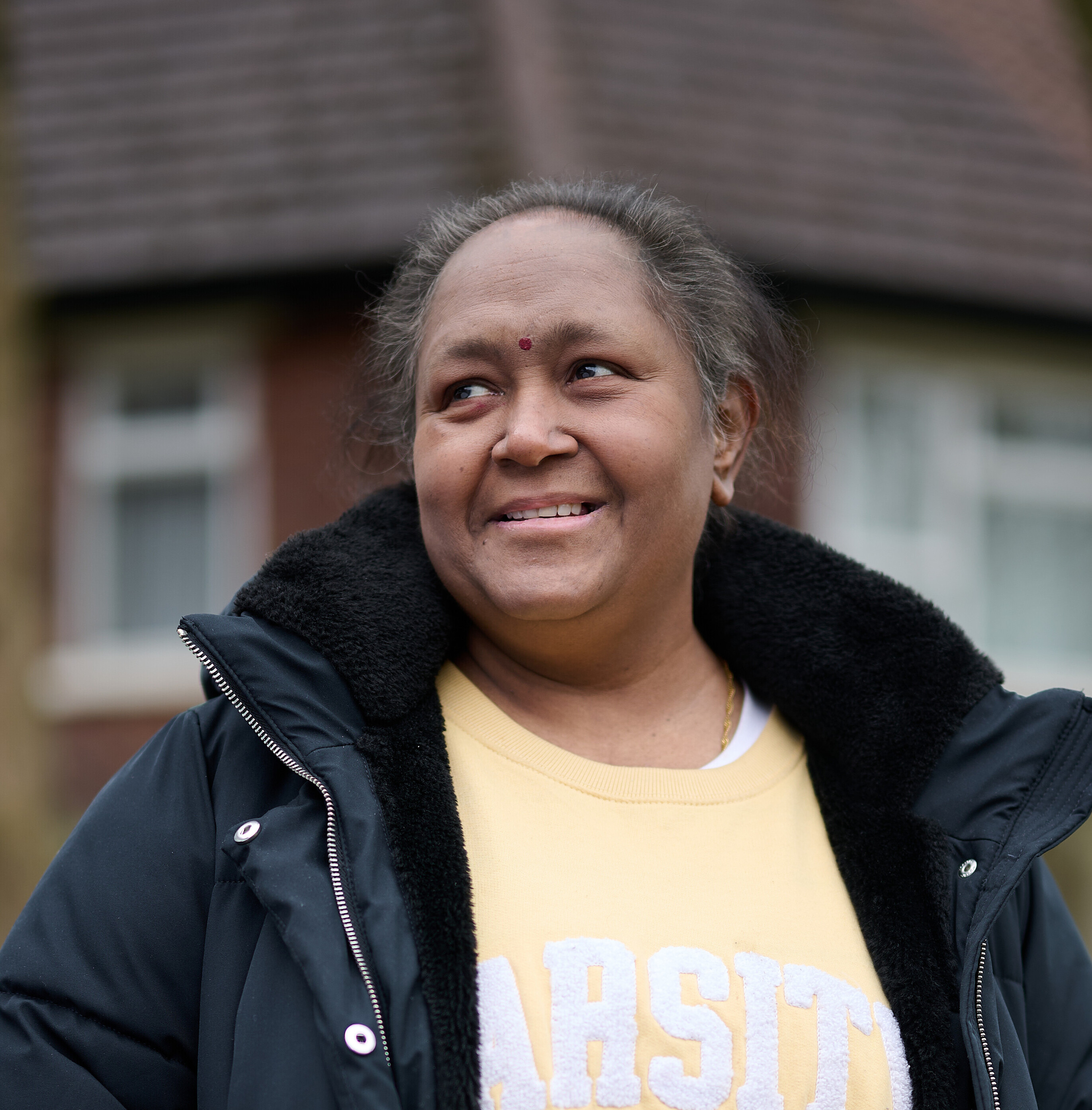 A smiling woman standing outside in a garden.