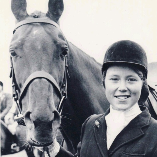 Beverly is posing with a horse. She is wearing horse riding gear. The photo is in black and white.