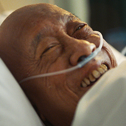 A smiling man in a hospital bed with an oxygen tube