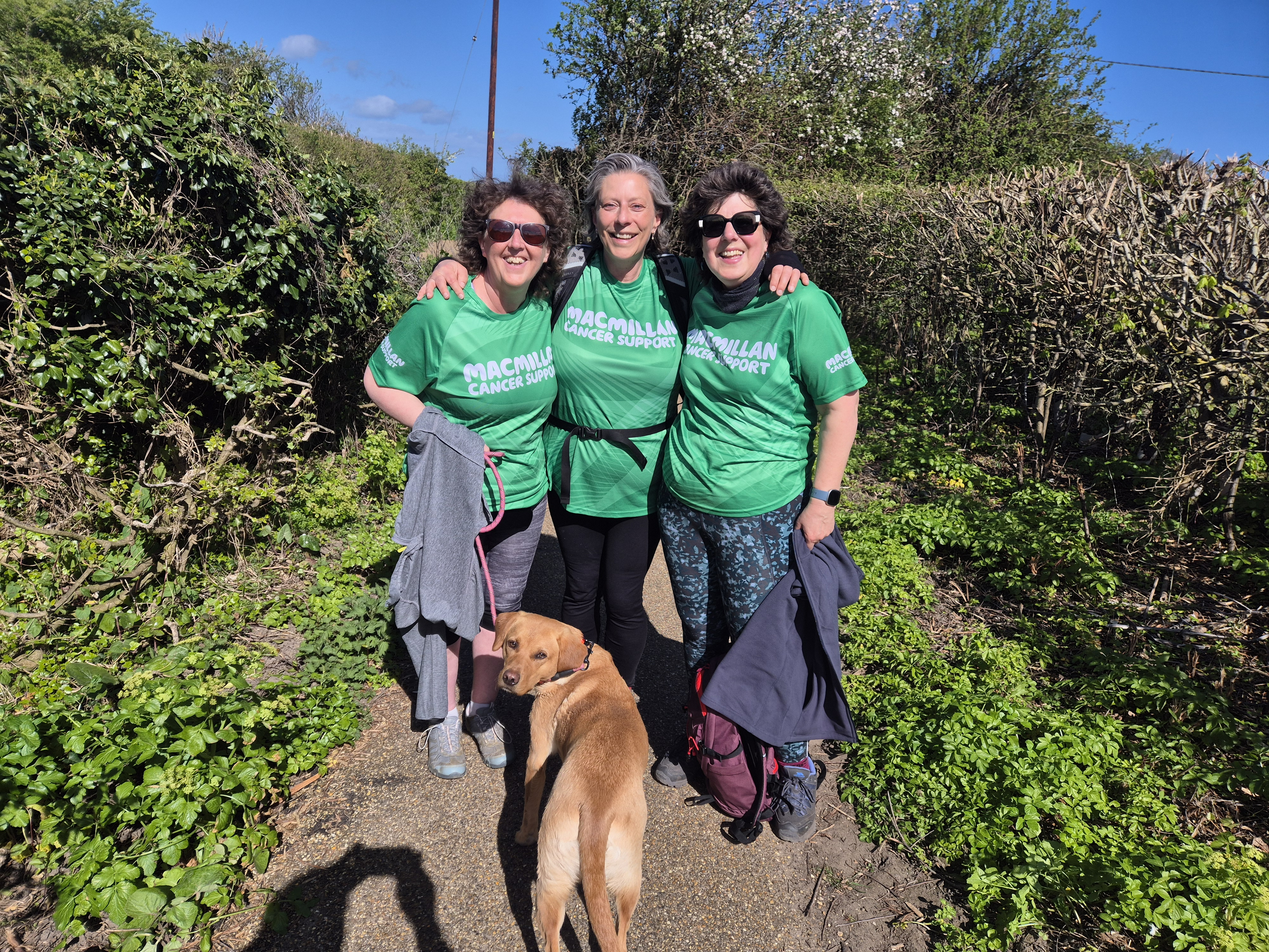 Lizzie with two other women, all wearing Macmillan t-shirts out hiking with a dog
