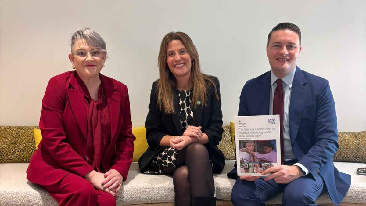 Three people sit on a bench in a meeting space, with one holding a printed report featuring images and text on the cover.