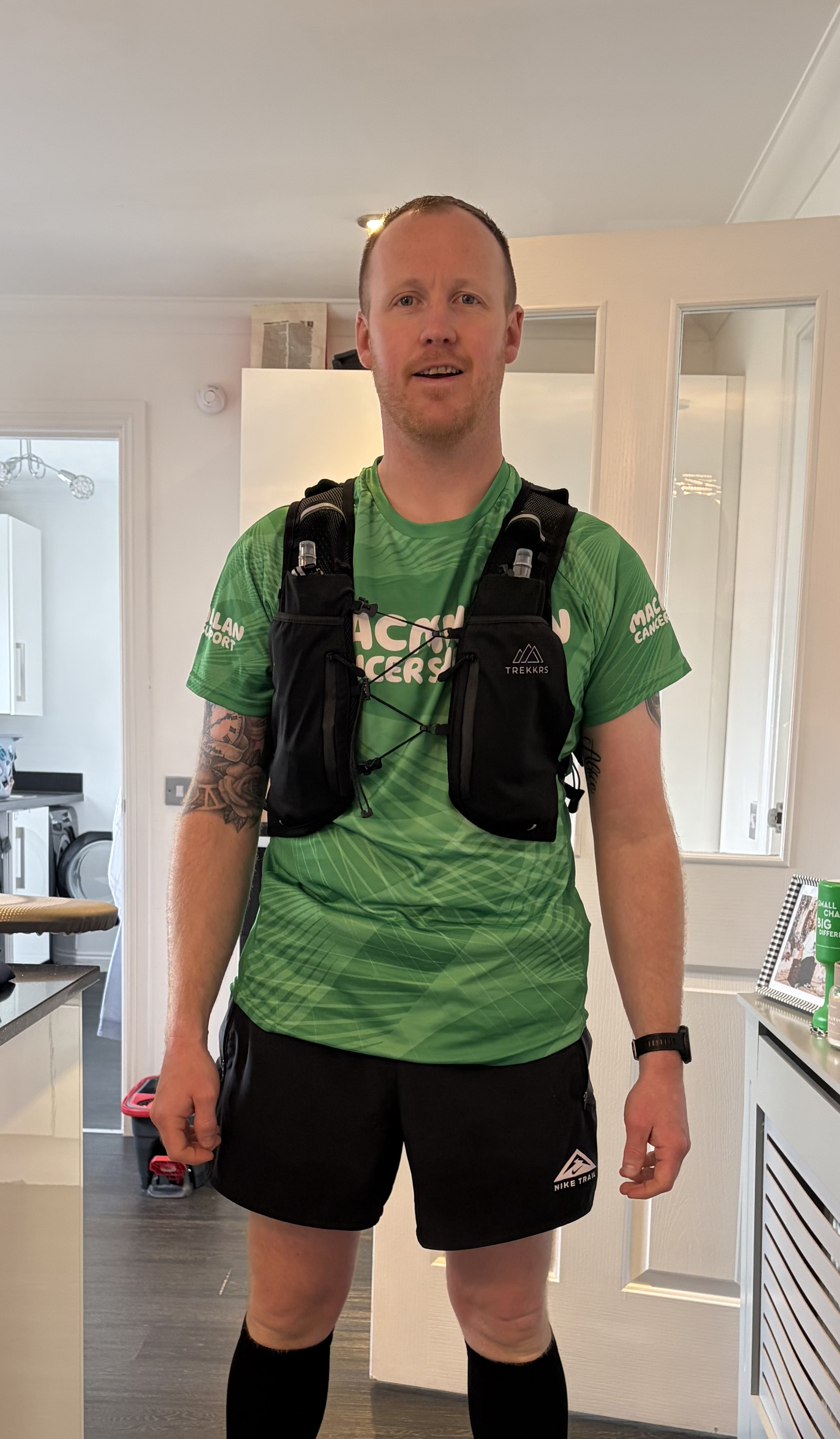 Lee in his Macmillan running vest and shorts standing in his house