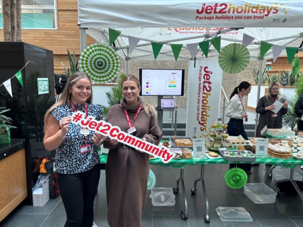 Jet2 employees at a coffee morning for Macmillan with lots of cakes and banners in the background.