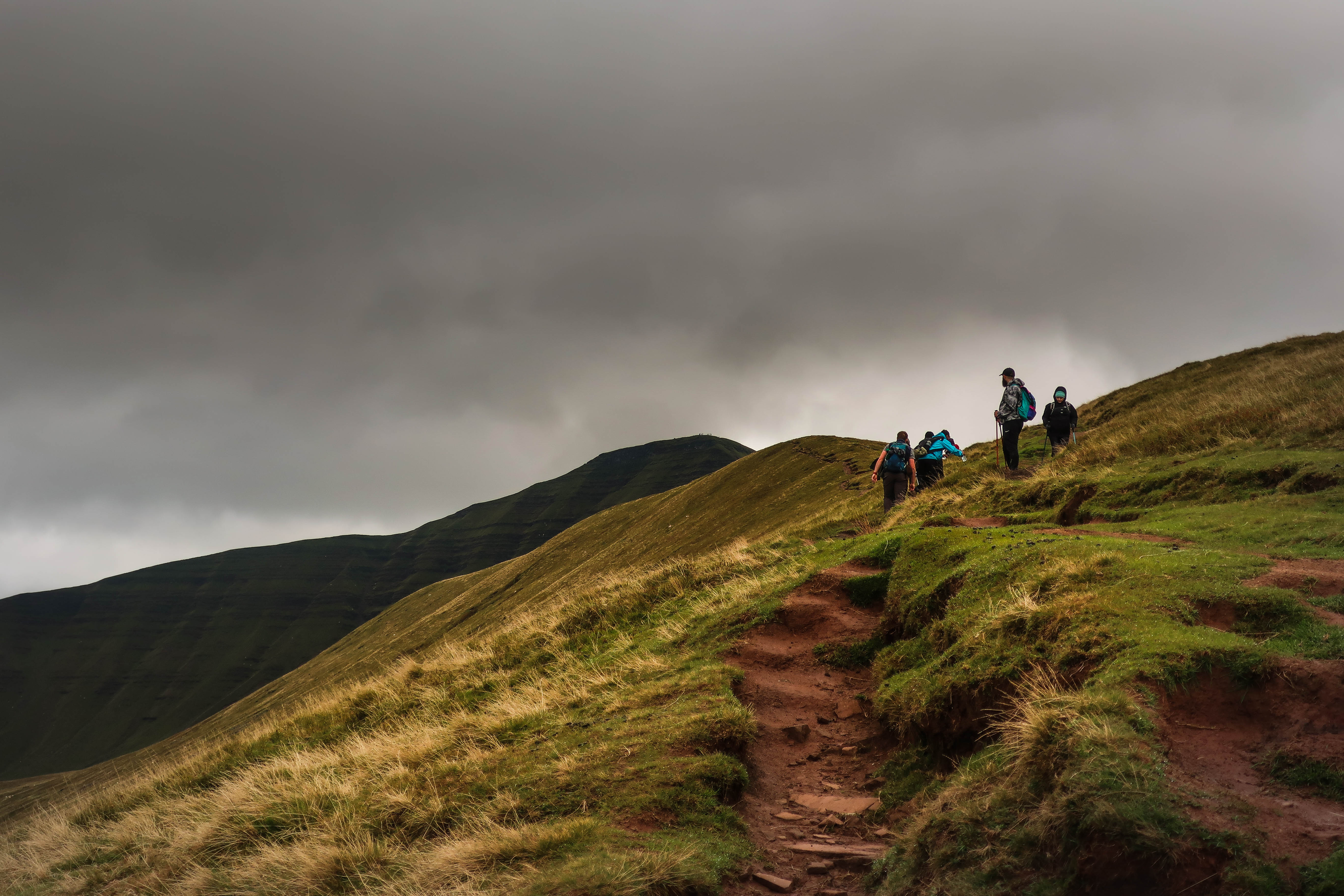 People hiking up Pen-y-Fan with a stormy sky
