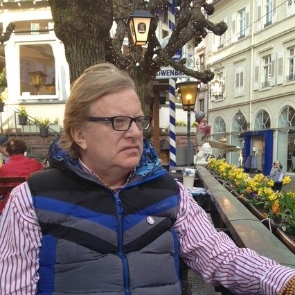 A white man in glasses sat at a table in a restaurant.