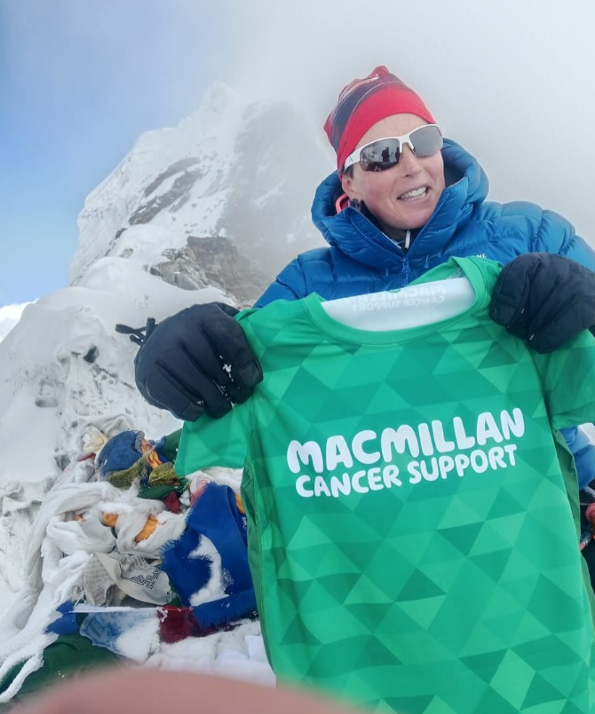 Shaunna on a mountain holding a Macmillan running t-shirt