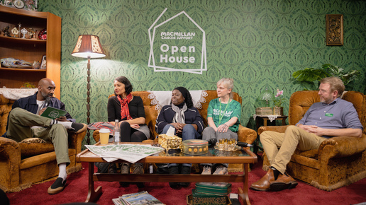 A group of people are sat together on sofas and armchairs around a coffee table. They are taking part in Macmillan's Open House. This event was co-created with Black and South Asian communities to talk about cancer, culture, and everything in between.