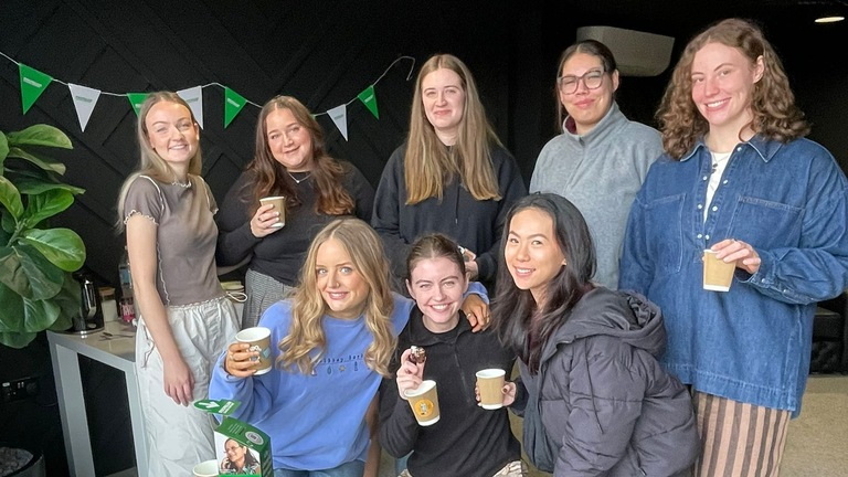 Juliette and the Wholesome Girls Club at their Coffee Morning. They are standing together behind a table full of delicious treats for their event.