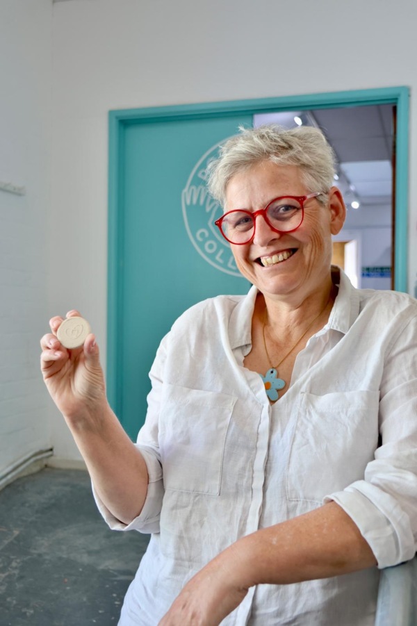 Zoe Cheale, artist from The Potthouse Collective, holding a clay token featured as part of the garden’s reflection pool.