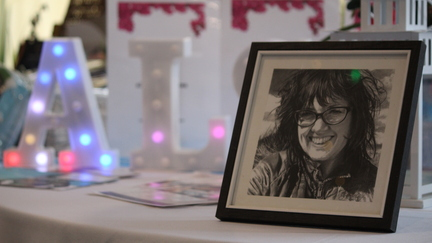 A photo of Alison in a frame set up on a table at a fundraising event.