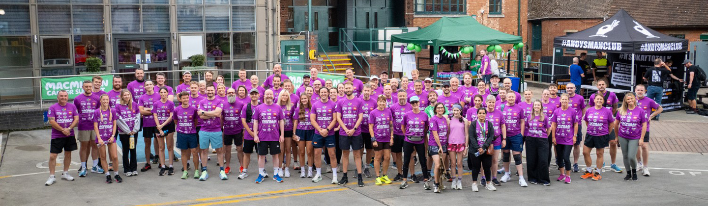 A large group of runners at the Greene King Brewery Run. They are standing side by side at a Greene King pub, they are all wearing purple running tops.