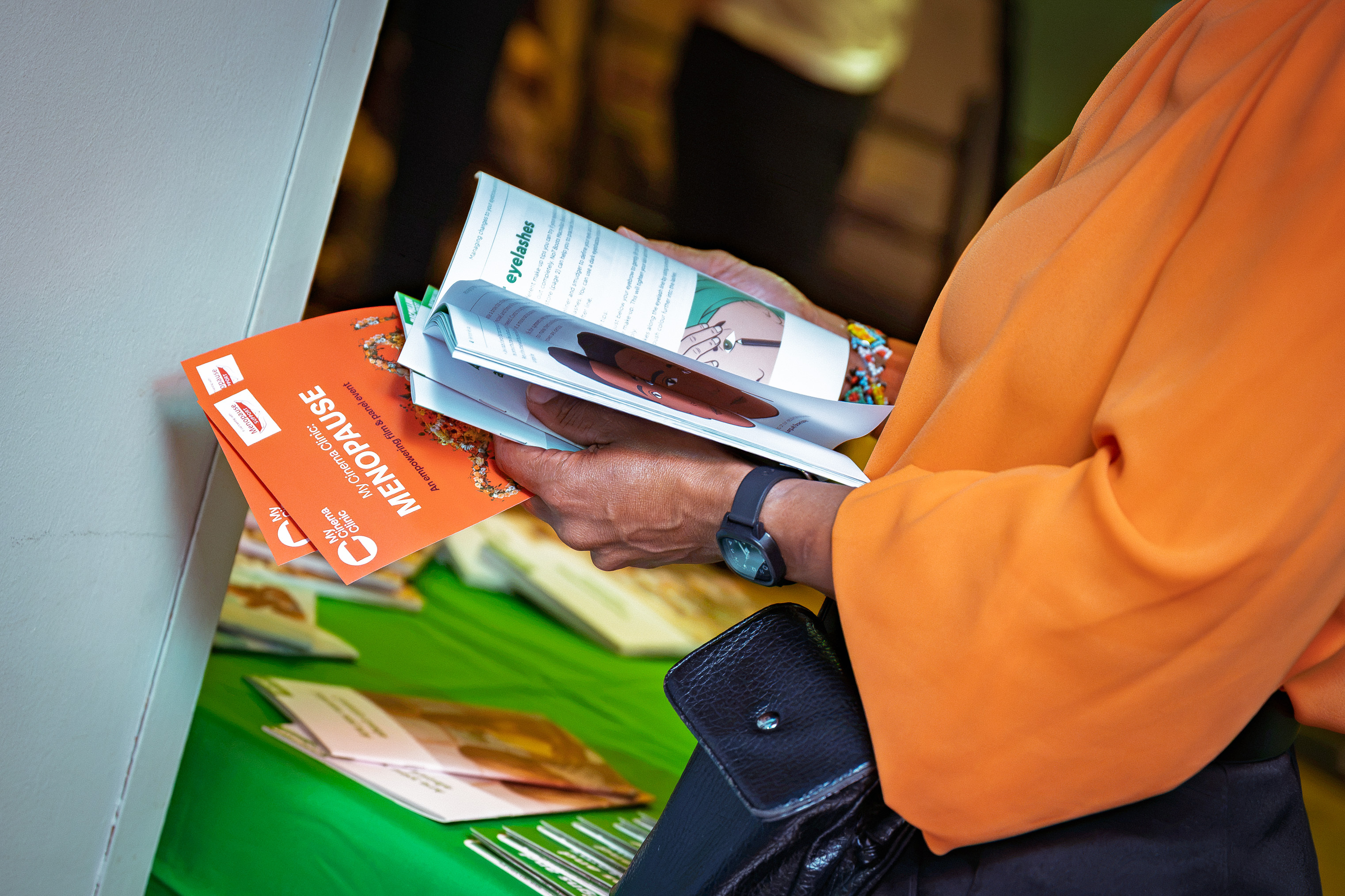 Person in orange top is holding cancer information booklets.