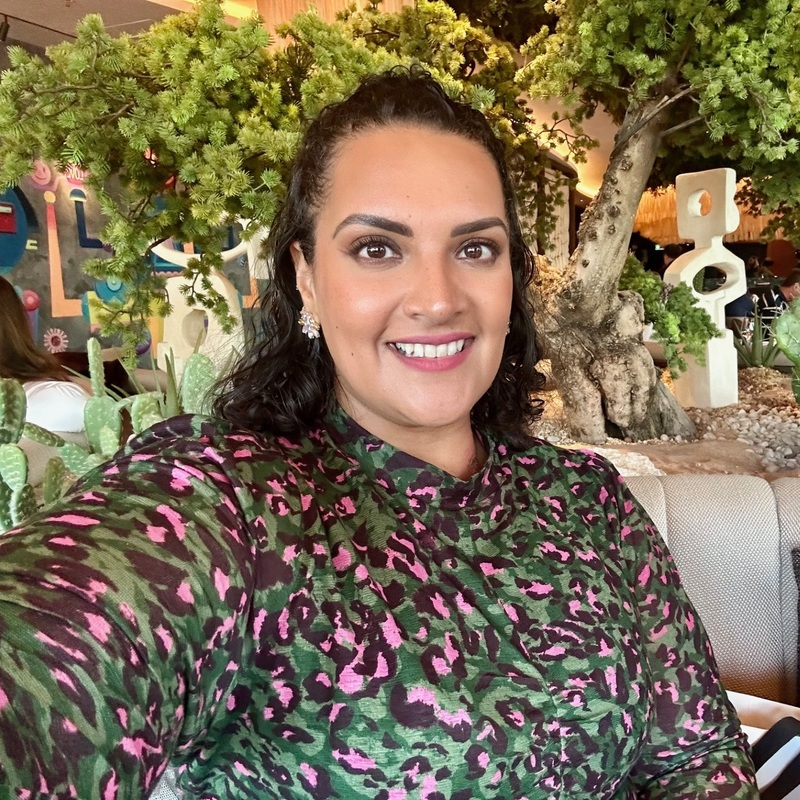 A person sitting in a restaurant surrounded by plants and trees, photographed during a period of living with cancer