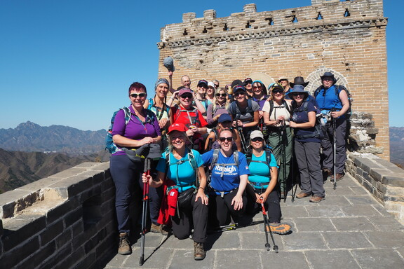 A large group of hikers standing together and posing for a photo on the Great Wall of China.