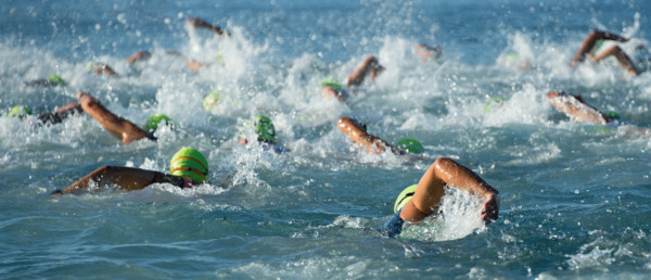 Group of open water swimmers swimming with green swimming caps on