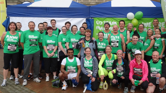 Large group of Team Macmillan runners posing for the camera and wearing green Macmillan t-shirts and running vests.