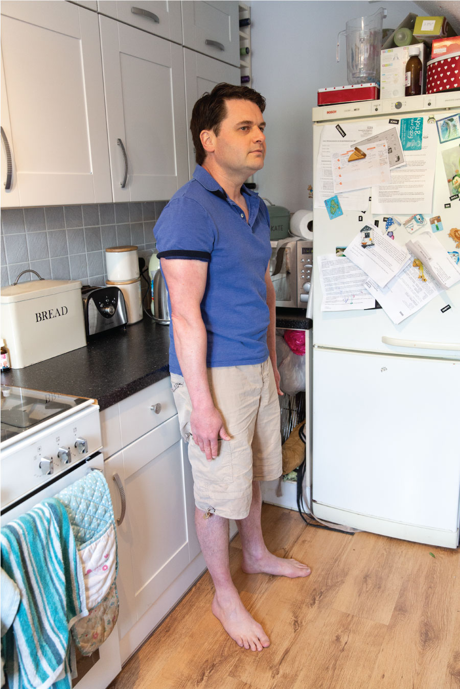 Position 4. A man stands upright supporting his weight against a supported surface. His arms and shoulders are relaxed.