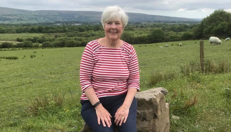 A lady sitting on a rock in the outdoors