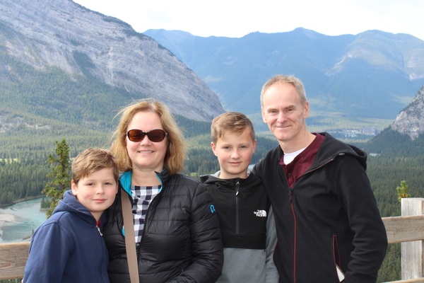A man and a woman with two male children standing in front of a mountainous landscape