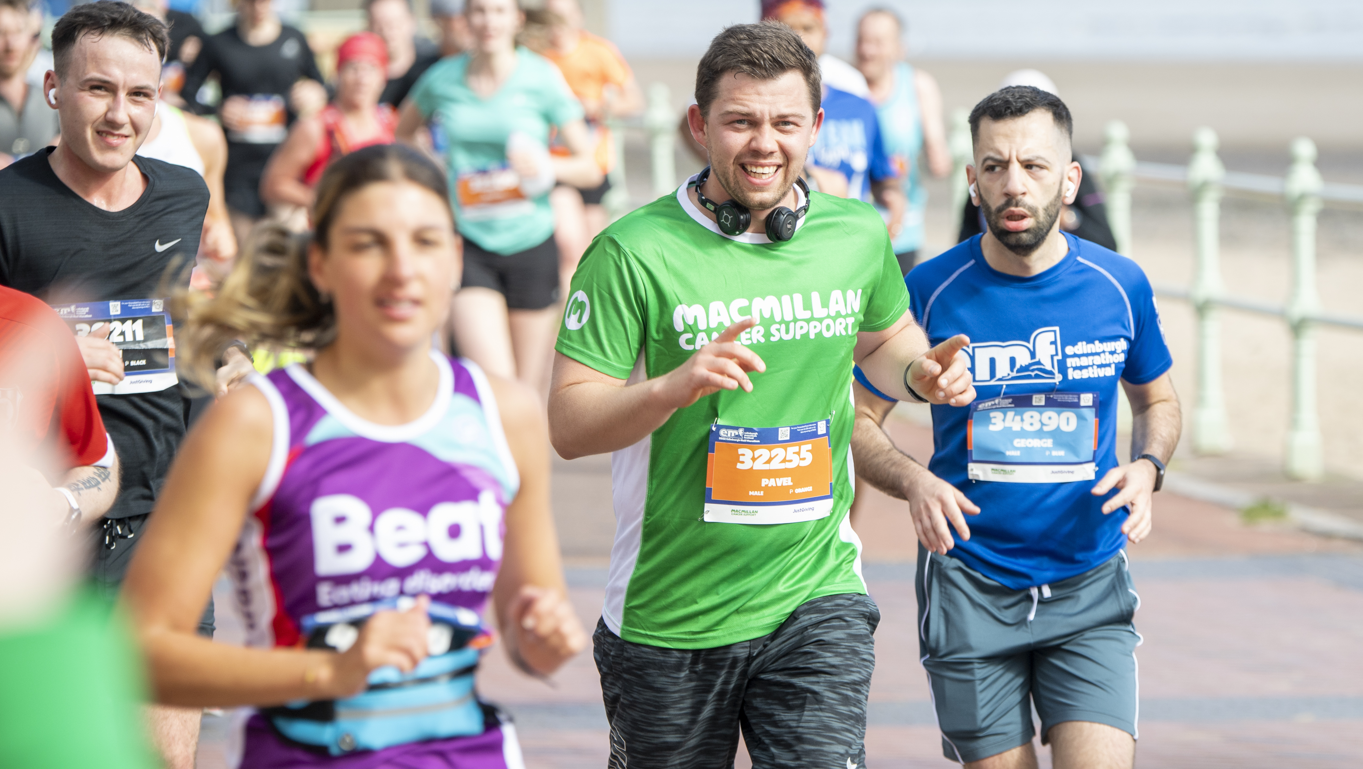 Man surrounded by other runners in a Macmillan running t-shirt
