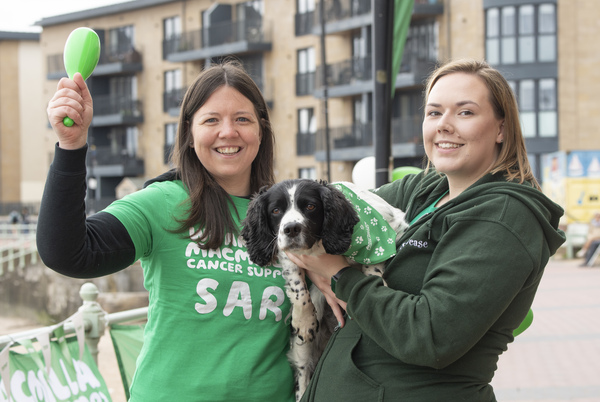 Two women in Macmillan t-shirts holding a dog