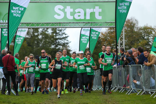 Lots of runners wearing Macmillan green coming over the start line