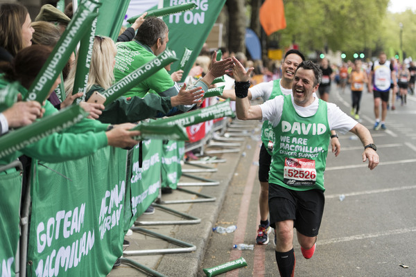 Two Macmillan runners high fiving Macmillan volunteers as they run past