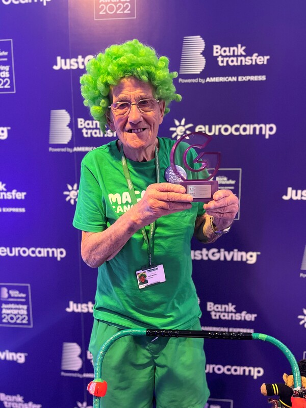 John wearing a green Macmillan wig posing with his JustGiving award