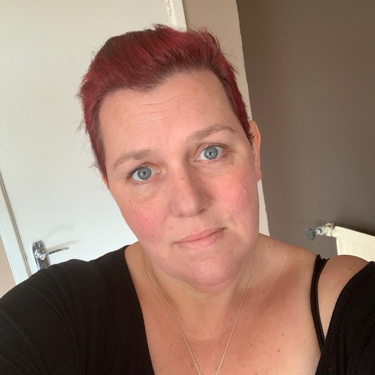 A lady with short red hair and wearing a black top.