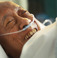 A smiling man in a hospital bed with an oxygen tube